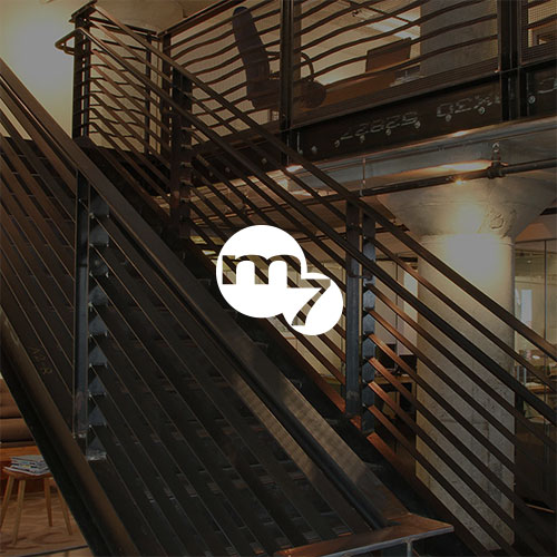 Modern stairway in large room with Marker Seven logo overlay in center