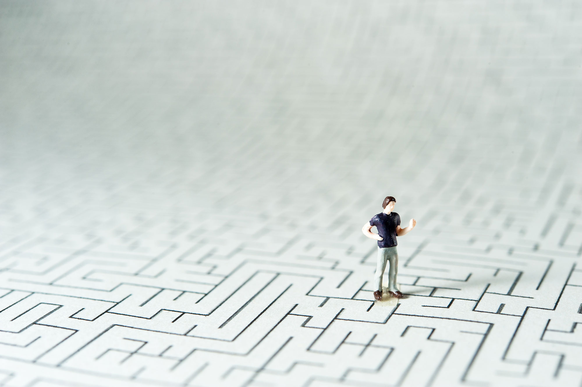 Person figurine on a drawn maze on paper